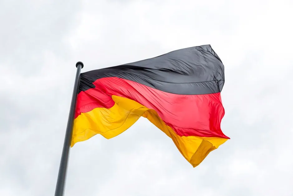 Vibrant German flag flying against a backdrop of a cloudy sky, symbolizing national pride.